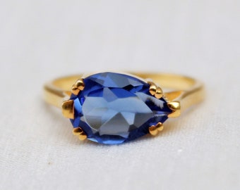 Puede incluir: Un anillo de oro con una piedra preciosa azul en forma de pera.