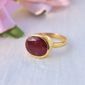 Pu&ograve; includere: Un anello d'oro con una grande pietra preziosa di rubino di forma ovale. Il rubino &egrave; di colore rosso intenso e ha una taglio sfaccettato.