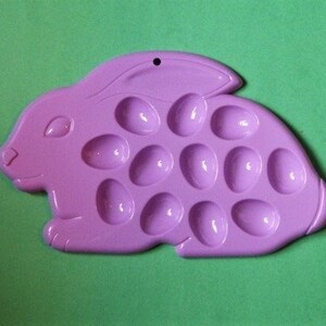 May include: A purple plastic bunny-shaped mold with 16 egg-shaped depressions. The mold is designed for making Easter treats.