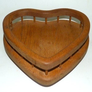 May include: A wooden heart-shaped bowl with a decorative slatted design around the rim. The bowl is made of natural wood and has a warm brown color.