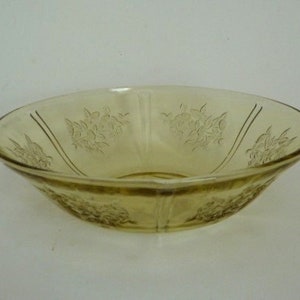 May include: A clear glass bowl with a floral pattern. The bowl is yellowed with age and has a slightly rippled surface.