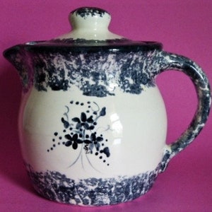 May include: A white ceramic teapot with a blue and white floral design and a speckled glaze. The teapot has a lid and a handle.