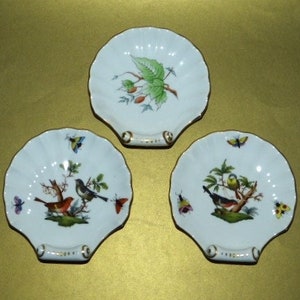 May include: Three white porcelain shell-shaped dishes with gold trim. Each dish features a different hand-painted bird and butterfly design.