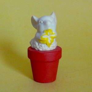 May include: A white ceramic figurine of a mouse holding a yellow flower, sitting in a red flower pot.