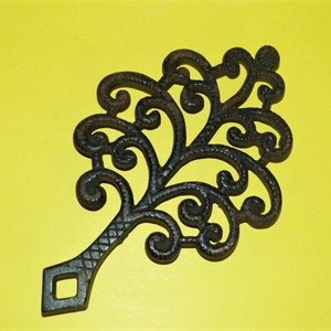 May include: Black cast iron trivet shaped like a stylized tree with a diamond-shaped handle.
