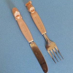May include: A set of two vintage children's cutlery featuring cartoon character handles. The knife has a pink handle with a cartoon face and the words "BRUNO" printed on it. The fork has a pink handle with a cartoon face and the words "FOR ALL" printed on it.