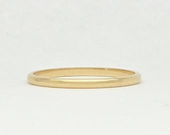 Puede incluir: Un anillo de banda de oro macizo sencillo con un acabado liso y pulido y un perfil redondeado. El anillo presenta un diseño circular continuo y liso sin piedras, grabados ni adornos adicionales, mostrando una apariencia dorada metálica clásica.