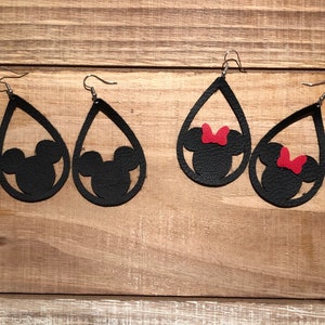 May include: A pair of black leather teardrop-shaped earrings with a cutout of Mickey Mouse and Minnie Mouse. The Minnie Mouse earring has a red bow.