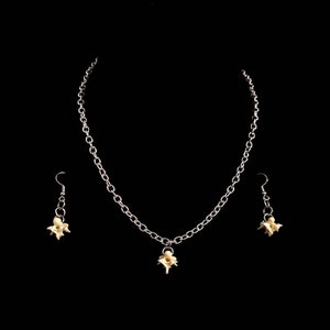 May include: A jewelry set consisting of a silver-toned metal chain necklace and a pair of matching drop earrings. The necklace features a single off-white, bone-like vertebrae pendant at the center, while each earring displays a similar small vertebrae.