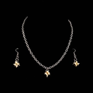 May include: A silver chain necklace with a delicate flower pendant and matching earrings. The flower charms are a pale yellow color.