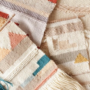 Può includere: Una collezione di arazzi da parete tessuti con motivi geometrici in tonalità beige, marrone, pesca, turchese e giallo. Gli arazzi sono realizzati con fibre naturali e presentano dettagli a frangia.
