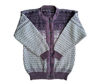 May include: A cream and purple knitted cardigan with a button-up front. The sweater features a detailed pattern with geometric and floral designs. The sleeves and body have a dotted pattern, and the cuffs and collar are a solid purple color.