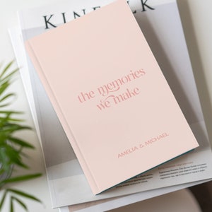 May include: A pink hardcover journal with the text "the memories we make" in pink script. The names "Amelia & Michael" are printed in pink at the bottom of the cover.