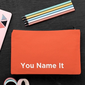 May include: Orange canvas pencil case with a zipper closure. The case has white text that reads "You Name It".