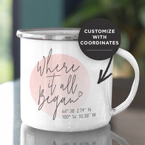 May include: White enamel camping mug with a pink circle and the text "Where it all began" with a heart symbol. The mug also has coordinates printed on the bottom: 46° 38′ 2.79" N 100° 14' 10.38" W.