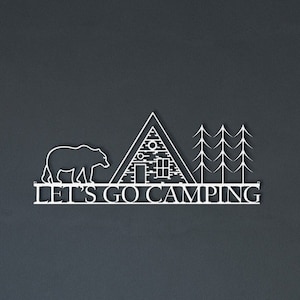 Könnte beinhalten: Weiße Wandkunst aus Metall mit einem Bären, einer Hütte und Bäumen. Der Text "Let's Go Camping" befindet sich unter dem Bild.