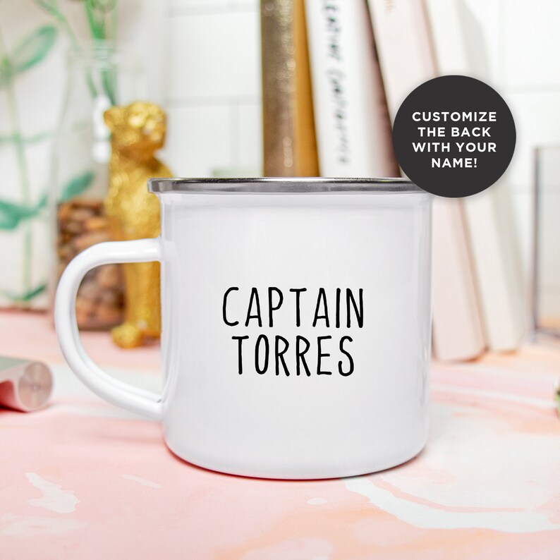 May include: White enamel mug with a silver rim and handle. The mug features the text "CAPTAIN TORRES" in black, centered on the front. A black circle with white text reads "CUSTOMIZE THE BACK WITH YOUR NAME!"