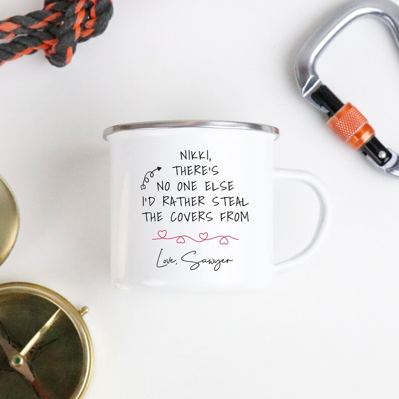 May include: White enamel camping mug with a black handwritten message that reads "Nikki, there's no one else I'd rather steal the covers from. Love, Sawyer". The message is surrounded by five small red hearts.