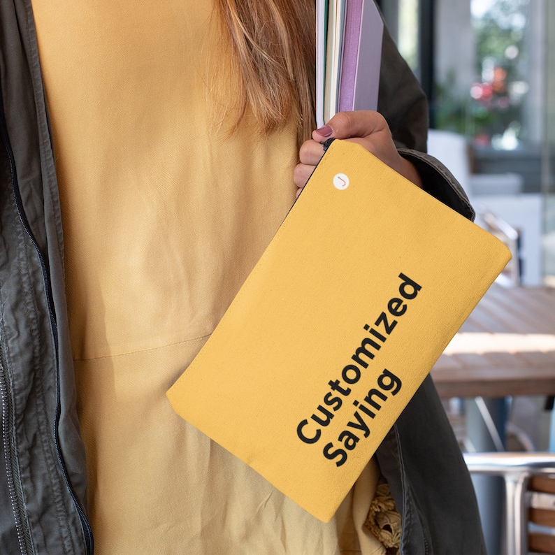 May include: A yellow canvas pouch with a black zipper and the text "Customized Saying" printed on the front.