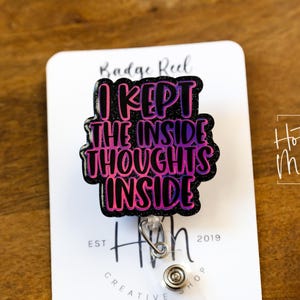 May include: A black and pink glitter badge reel with the text "I kept the inside thoughts inside". The reel is attached to a silver retractable badge holder.