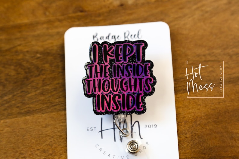 May include: A black and pink glitter badge reel with the text "I kept the inside thoughts inside". The reel is attached to a silver retractable badge holder.