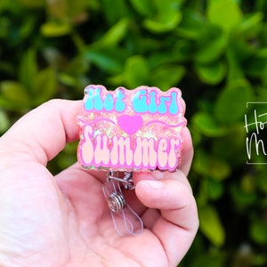 Pode incluir: Porta-crach&aacute; de resina rosa e azul com glitter e o texto "Hot Girl Summer" e um cora&ccedil;&atilde;o rosa.