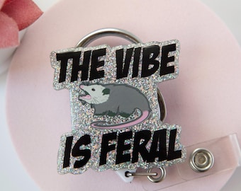 Carrete retráctil de acrílico con la divertida insignia "The Vibe Is Feral"