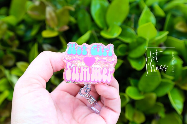 Pode incluir: Porta-crach&aacute; de resina com glitter rosa e turquesa com o texto "Hot Girl Summer" e um cora&ccedil;&atilde;o rosa.