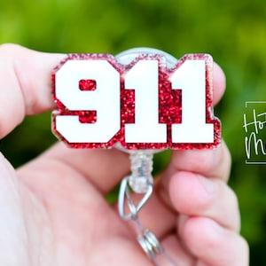 May include: Red glitter 911 badge reel with a white background and a silver retractable cord.