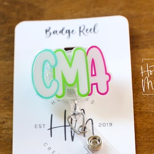 K&ouml;nnte beinhalten: Ein Ausweis-Rollhalter mit den Buchstaben "CMA" in einem Farbverlauf aus Hellblau, Gr&uuml;n und Pink. Der Rollhalter hat einen Stethoskop-Anh&auml;nger und den Text "Hot Mess Creative Shop" und "Est 2019".
