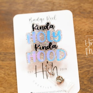May include: A blue and white glitter badge reel with the text "Kinda Holy Kinda Hood" and the text "Hot Mess Creative Shop" on a white card.