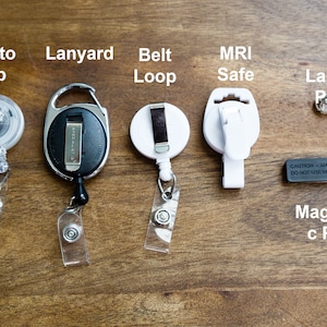 May include: Assortment of badge holders and accessories, including an alligator clip, lanyard, belt loop, MRI-safe clip, lapel pin, and magnetic pin. The image includes text labels for each item, displayed on a wooden surface.