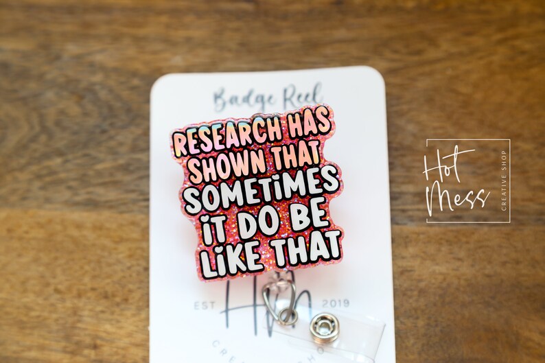 Op de afbeelding: Roze glitter badge reel met de tekst "RESEARCH HAS SHOWN THAT SOMETIMES IT DO BE LIKE THAT".