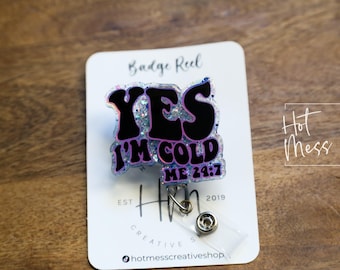 May include: A clear badge reel with a pink and black glitter design that says "YES I'M COLD ME 24:7".