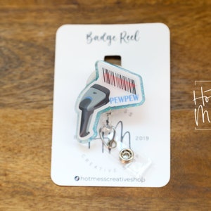 May include: A blue and white badge reel with a barcode scanner design. The scanner has the text "PEWPEW" on it. The badge reel is on a white card with the text "Badge Reel" and "Hot Mess Creative Shop" printed on it.