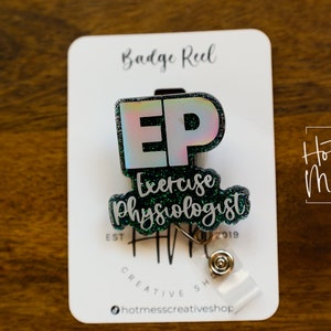 Può includere: Un portabadge con paillettes verdi con una "EP" bianca e il testo "Exercise Physiologist". Il portabadge è su una carta bianca con il testo "Badge Reel" e "Hot Mess Creative Shop".