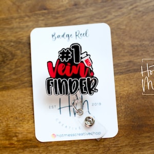 Puede incluir: Un carrete de credencial rojo y negro con el texto "#1 Vein Finder" y un pequeño gráfico de jeringa roja. El carrete de credencial está unido a una tarjeta blanca con el texto "Hot Mess Creative Shop" y "Badge Reel".