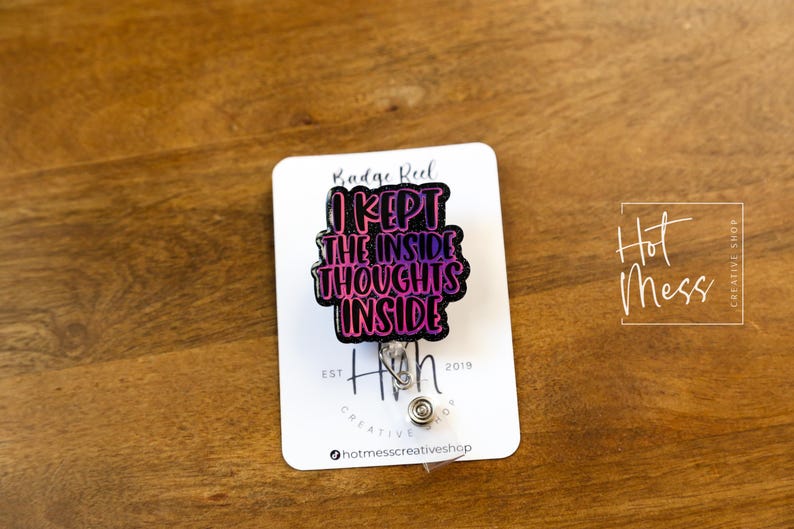 May include: A black badge reel with a pink and purple gradient design. The text on the reel reads "I kept the inside thoughts inside". The reel is attached to a silver retractable badge holder.