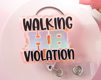 May include: A pink glitter badge reel with the text "WALKING HR VIOLATION" in black. The letters "HR" are in orange and blue. The badge reel has a silver metal ring and a clear plastic clip.