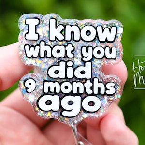 Könnte beinhalten: Ein klarer, glitzernder Ausweis-Rollenhalter mit dem Text "I know what you did 9 months ago" in schwarzer Schrift. Der Ausweis-Rollenhalter hat eine wolkenartige Form und die Worte "Hot Mess Creative Shop" sind in der Ecke.