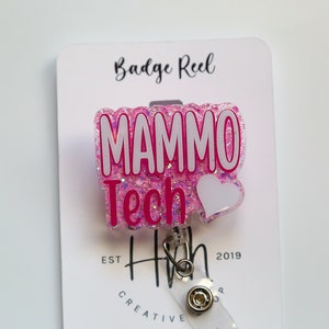 May include: Pink glitter badge reel with a white heart and the text "MAMMO Tech" in white letters with pink outlines. The text "EST" and "2019" are visible below the badge reel.