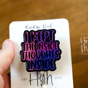 May include: A black and purple glitter badge reel with the text "I kept the inside thoughts inside".