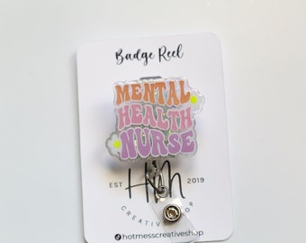 May include: A badge reel with the words "MENTAL HEALTH NURSE" in orange and purple, with a daisy accent. The reel is attached to a white card with the words "Badge Reel" at the top and "HM Creative Shop" at the bottom.