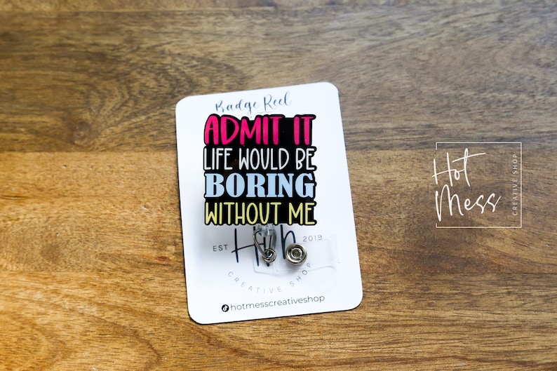 May include: White badge reel with the text "Badge Reel ADMIT IT LIFE WOULD BE BORING WITHOUT ME" in colorful letters. The badge reel has a clear plastic cover with two silver badge clips.