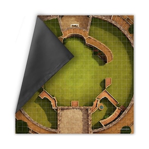 May include: A detailed, top-down view of a gaming mat featuring a circular arena design. The mat has a green grassy area, stone pathways, and architectural elements. A black fabric corner is folded over, revealing the mat's underside.