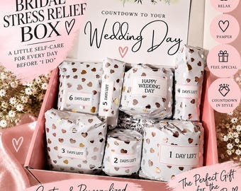 May include: A pink gift box containing multiple items wrapped in white paper with rose gold hearts. Each package features a label counting down from 6 days to the wedding day. A card inside reads Countdown to your Wedding Day with floral accents.