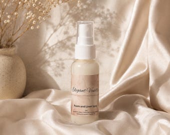 May include: A clear plastic spray bottle containing a milky white liquid, topped with a white pump nozzle. The label features a beige marble pattern with the text Elegant Vanilla, Room and Linen Spray, 2oz, and a list of ingredients.