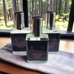 May include: Three glass bottles of Pixie Dust perfume, each with a silver cap and a black label with pink text. The label reads "Pixie Dust Perfume 1 oz".