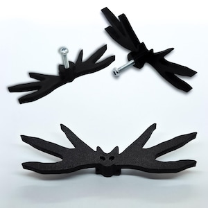 May include: Three black bat-shaped cabinet pulls with silver screws. The pulls feature a stylized bat design with pointed wings and a small face. They are made of a matte black material against a white background.