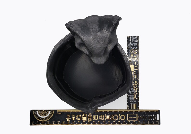 Puede incluir: Maceta de cer&aacute;mica negra con forma de cabeza de serpiente con una abertura redonda y ancha. La maceta tiene un di&aacute;metro de aproximadamente 15 cm.